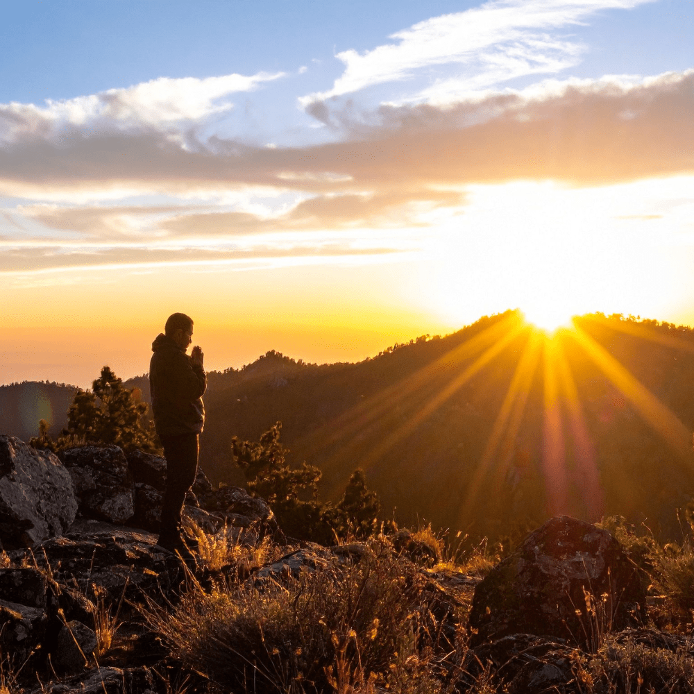person looking at sunrise at the top of the mountain