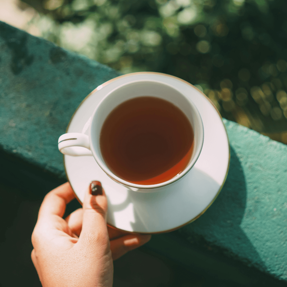 coffee cup on edge of patio with greenery