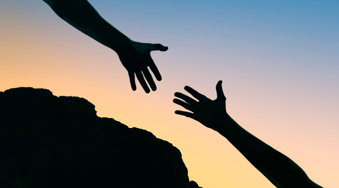 silhouette of hands reaching for each other at dawn 