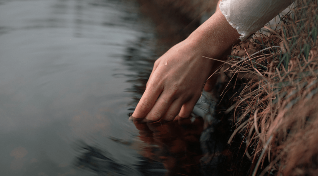 hand touching the surface of a lake
