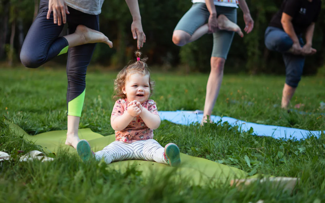parent with child on yoga mat in the grass